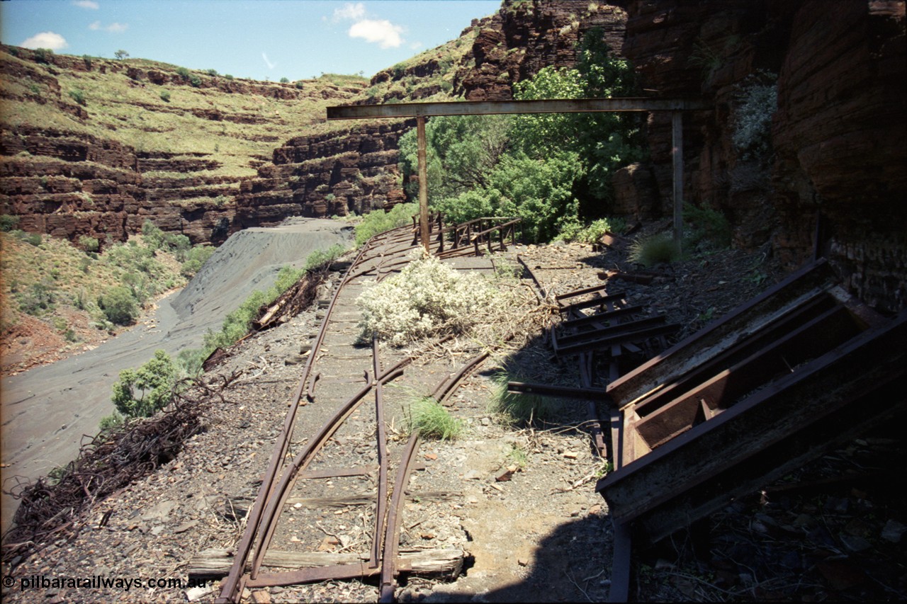 197-10
Wittenoom, Colonial Mine, asbestos mining remains, view looking south west of the open air service pit with gantry and locomotive storage roads with the battery off-take racks. The track used to continue around to the mine adits in the background.
