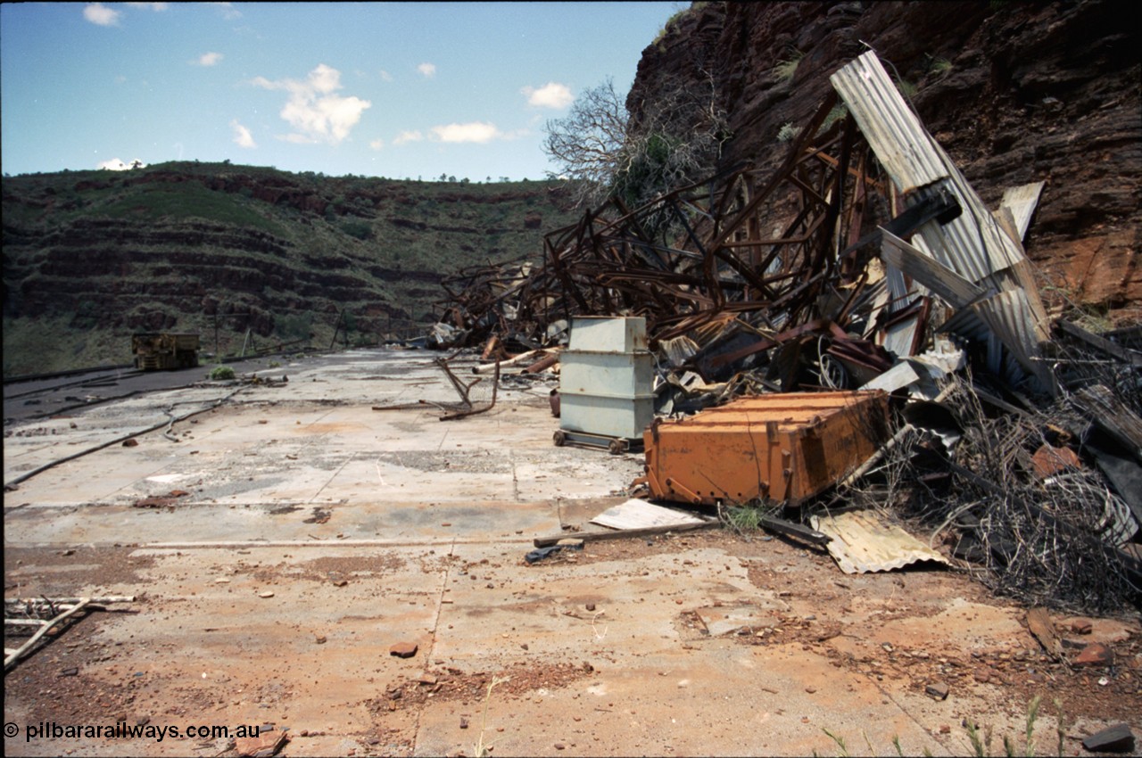 197-20
Wittenoom, Colonial Mine, asbestos mining remains, view of the demolished underground shift offices, upturned battery module, charging transformer, Mancha #4 battery locomotive on the right.
