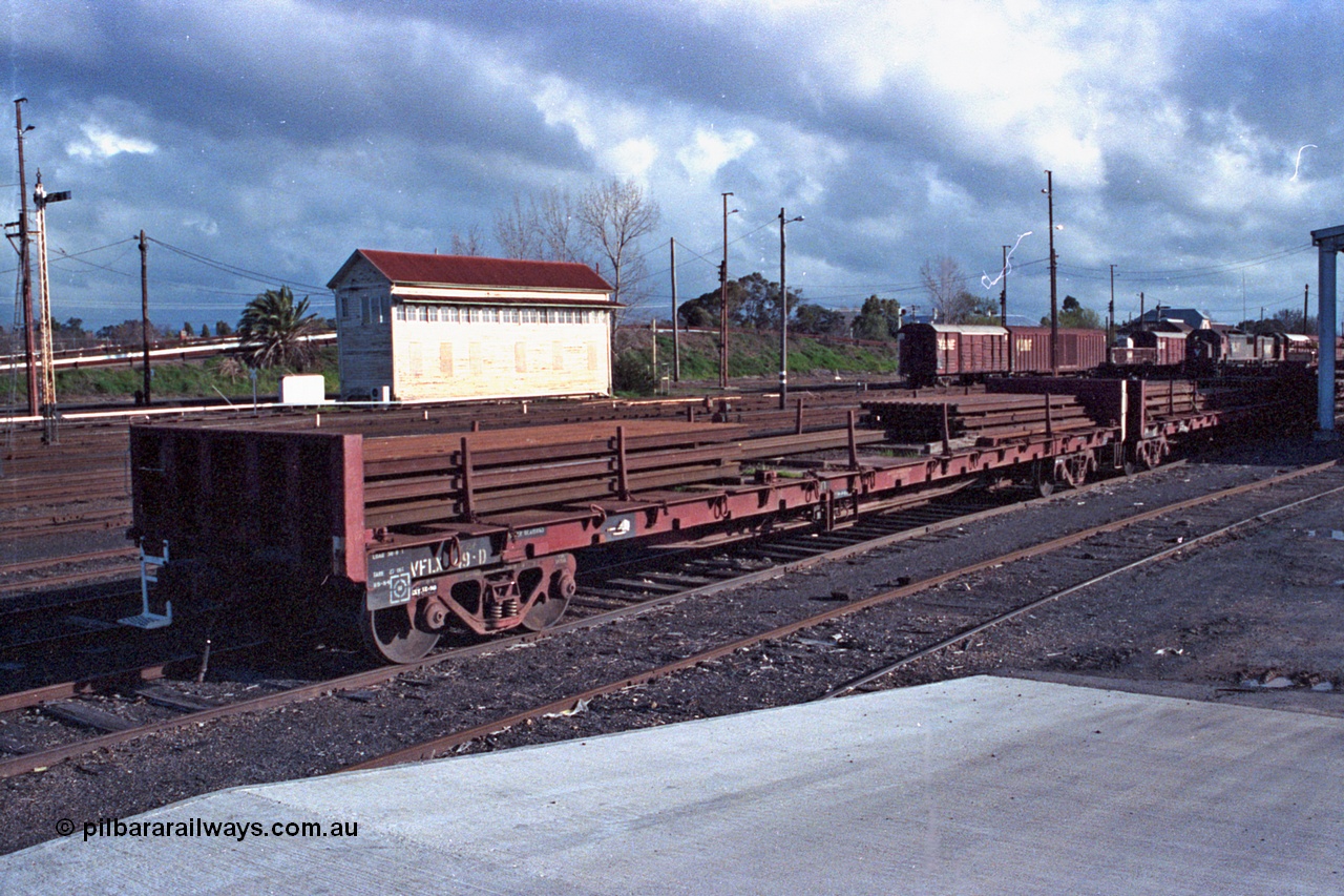 103-24
Benalla, broad gauge V/Line VFLX type bogie bulk end flat waggon VFLX 49 loaded with rail, Benalla B signal box in background. VFLX 49 was built by Victorian Railways Newport Workshops as an SFX type bulkhead flat waggon in 1968. This waggon was recoded to VQLX 138 in May 1991.
Keywords: VFLX-type;VFLX49;Victorian-Railways-Newport-WS;SFX-type;VQLX-type;