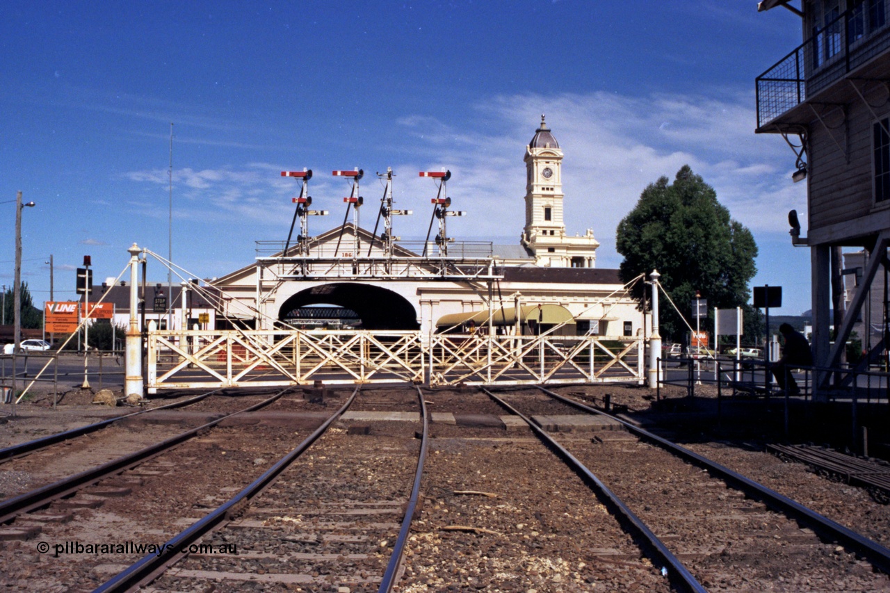 140-1-17
Ballarat station overview, station building clock tower and canopy, looking across Lydiard St with interlocked gates and semaphore signal gantry, Ballarat B signal box is at right.
