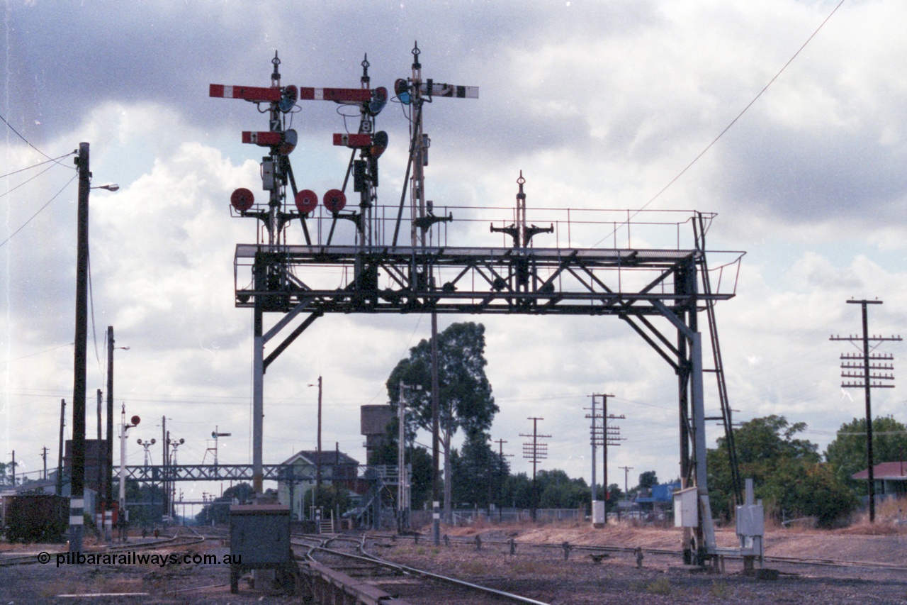 148-25
Wangaratta, Signal Bridge, Down Signal Posts 7, 8 and stripped 10 facing camera, Up Post 9 facing away. Signal Post 7 two arms and two discs, Top arm Home Signal 'A' to No.2 Road to Post 17, Bottom arm Calling-on Signal from 'A' to No. 2 Road towards Post 17. Left-hand Disc from 'A' to No. 4 or 5 Roads towards Post 19; or to No. 6 Road. Right-hand Disc from 'A' to No. 3 Road towards Post 17. Signal Post 8 two arms one disc, Top arm Home Signal from 'A' to No. 1 Road to Post 20, Bottom arm Calling-on Signal from 'A' to No. 2 Road towards Post 20. The Disc from 'A' to Carriage Dock. Stripped Disc Post 10 was from 'B' to No. 1 Road towards Post 20 and from 'B' to Carriage Dock.
