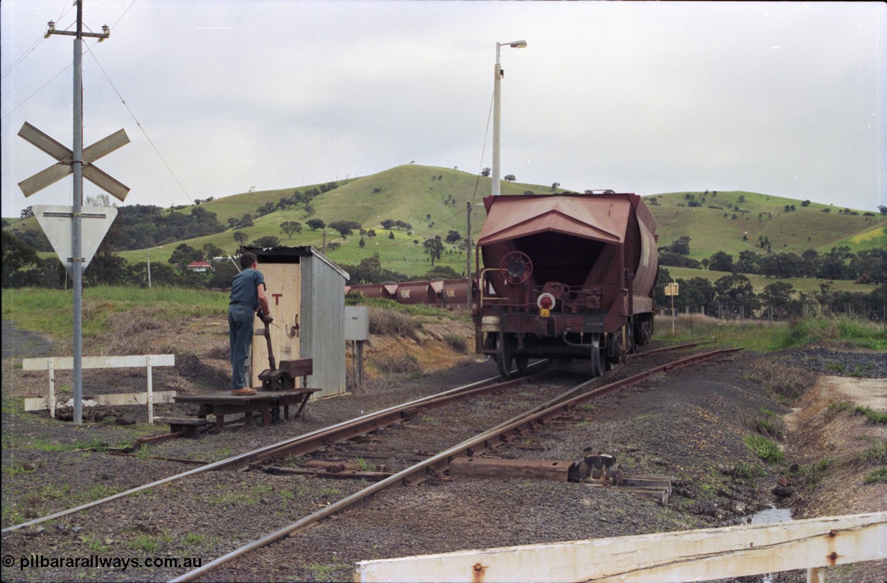 157-35
Kilmore East, Apex Quarry Siding, as the last waggon clears the points, the second person restores them to the reverse position before re-joining his train, handbrake end of VHQF type bogie quarry products waggon, end of train device, catch points and lever, telephone booth and grade crossing sign.
