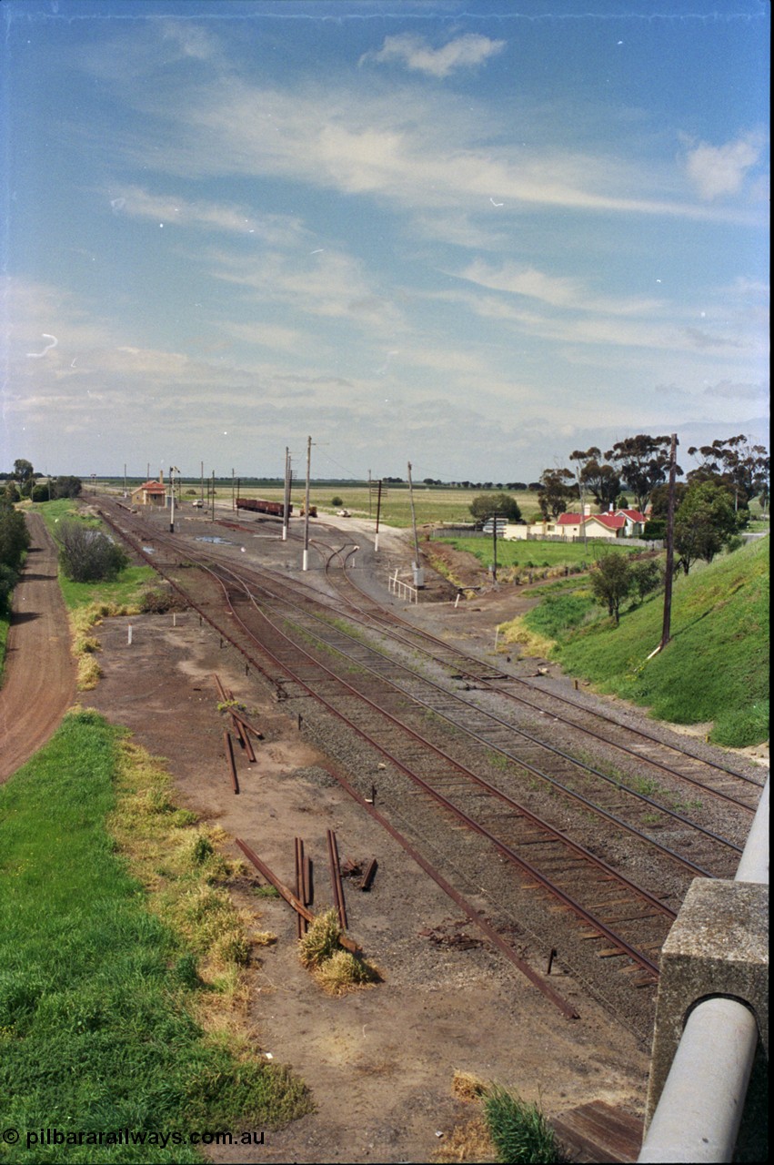 179-08
Gheringhap station yard overview from the elevated vantage point on the Midland Highway overpass, which was bought into use in 1967, looking east, the line on the left heading under the bridge is Siding C, in the middle is the Ballarat Line and then the Maroona Line, Sidings B with gypsum waggons can been seen to the right of the station building.
