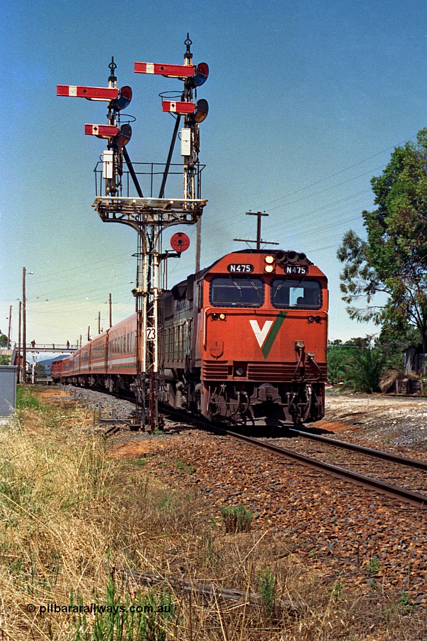 180-09
Wangaratta, looking south with the recently relocated up home semaphore signal post No.23 and the down V/Line broad gauge Albury passenger train behind the last member of the N class locomotives N 475 'City of Moe' Clyde Engineering EMD model JT22HC-2 serial 87-1204 passing with Z set and D van.
Keywords: N-class;N475;Clyde-Engineering-Somerton-Victoria;EMD;JT22HC-2;87-1204;