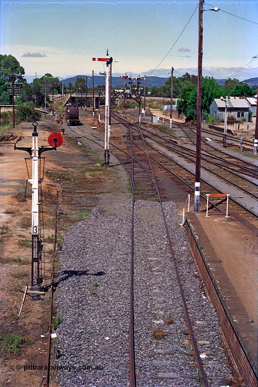 180-13
Wangaratta, yard view looking south from the southern footbridge, shows the Car Dock, disc signal post 13 and semaphore signal post 12, with a VTQF type bogie fuel waggon in the oil company siding. The area beyond signal post 13 and to the left was the former narrow gauge Whitfield line yard and transfer siding.
Keywords: VTQF-type;