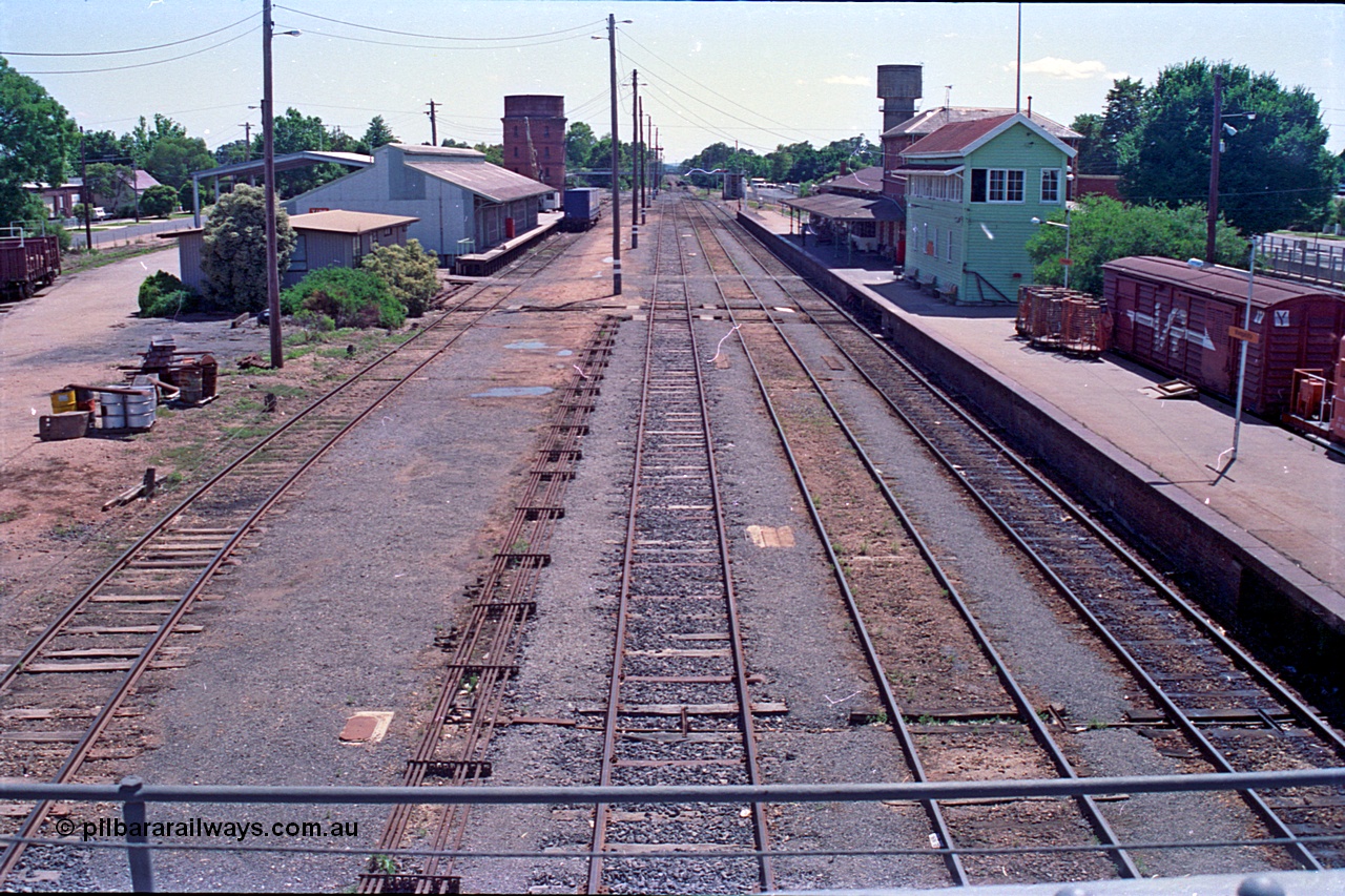 180-15
Wangaratta, rationalised yard view looking north from the southern end footbridge, show the removed No.4 Road, with goods shed, water tower and Freight Gate canopy on the left, and station building and platform with signal box and VLBY type bogie louvre parcels van on the right, point rodding is running along No.3 Road.
Keywords: VLBY-type;