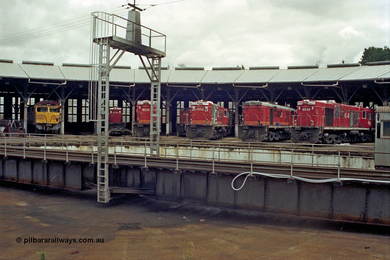 192-06
Junee, NSWSRA standard gauge locomotive depot, view across the turntable at roundhouse stalls 24 to 34 with 80 class ALCo CE615A 8045 in 25, and then ALCo RSD-20/DL-541 45 class units 4529, 4534, 4503, 4502, 4516 and 4540. The 45 class units are in the process of being sealed up for storage.
Keywords: AE-Goodwin;ALCo;Comeng-NSW;RSD-20;DL-541;CE615A;