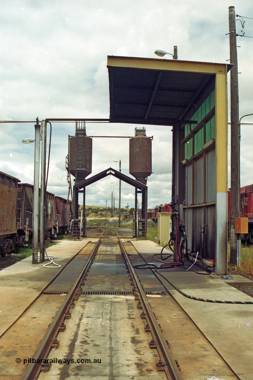 192-14
Junee, NSWSRA standard gauge locomotive depot, a view looking through the fuelling point with the sanding facility behind that, stored 45 class units on the right.
