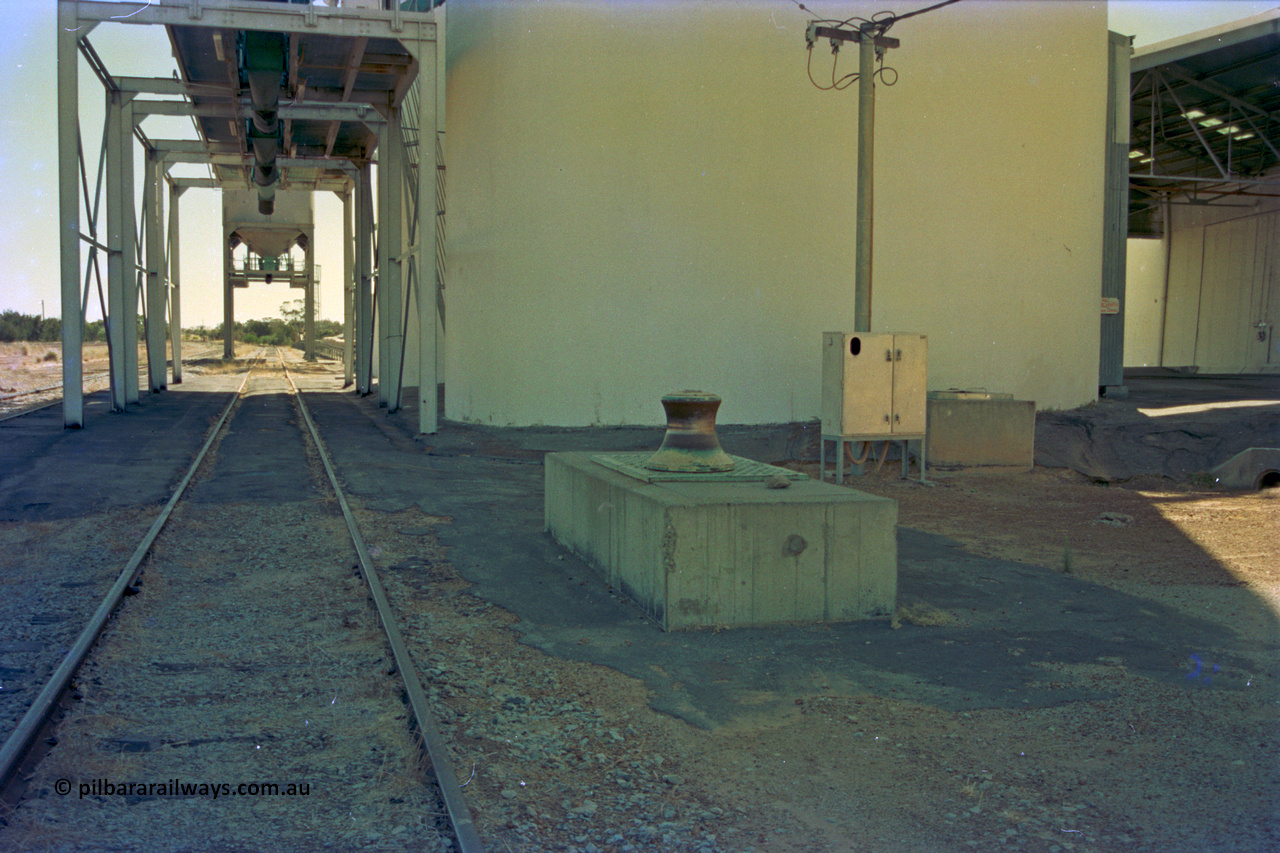 202-18
Meckering, looking west along the grain siding, capstan winch for assisting in moving grain waggons, the three loadout spouts for the concrete grain silos with the two overhead bunker loadouts visible beyond them.
