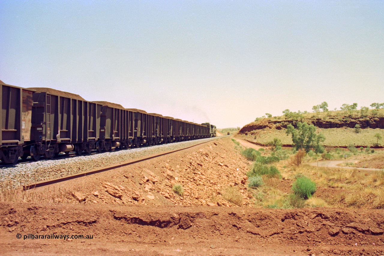 202-30
Yandi One, 307 km grade crossing sees a loaded train departing behind a CM40-8M and an CM40-8 unit with the rail grinder in the back track in the distance, the road curving around at the right goes to the Henry Walker camp.
