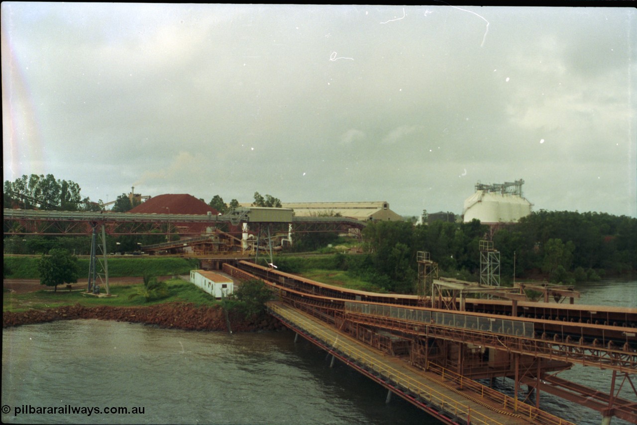 211-34
Weipa, Lorim Point view looking north east from the kaolin loader back towards the bauxite stockpiles, calcination shed and kaolin storage silos. The elevated conveyor is for kaolin, while the two conveyors running under the road to the right are the bauxite loading conveyors.
