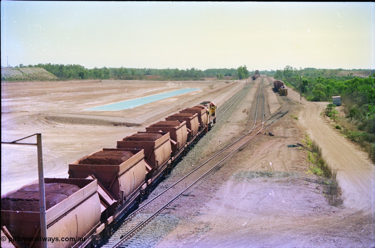 212-14
Weipa, a loaded train ex-Andoom Mine runs along the main with thirty two waggons at Lorim Point towards the dump station behind Comalco R 1004 Clyde Engineering EMD JT26C serial 90-1277 which is former Goldsworthy Mining loco GML 10.
