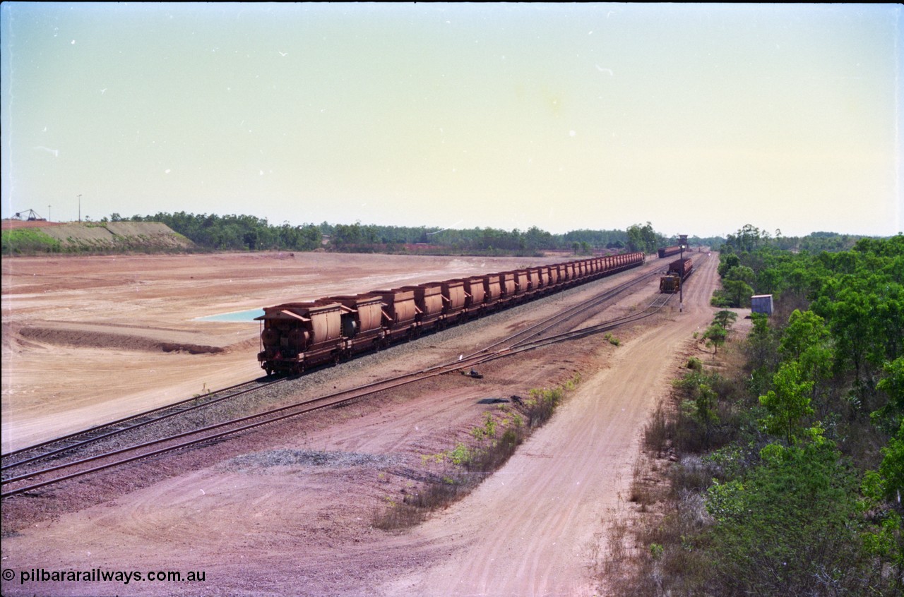 212-15
Weipa, a loaded train ex-Andoom Mine runs along the main with thirty two waggons at Lorim Point towards the dump station behind Comalco R 1004 Clyde Engineering EMD JT26C serial 90-1277 which is former Goldsworthy Mining loco GML 10.
