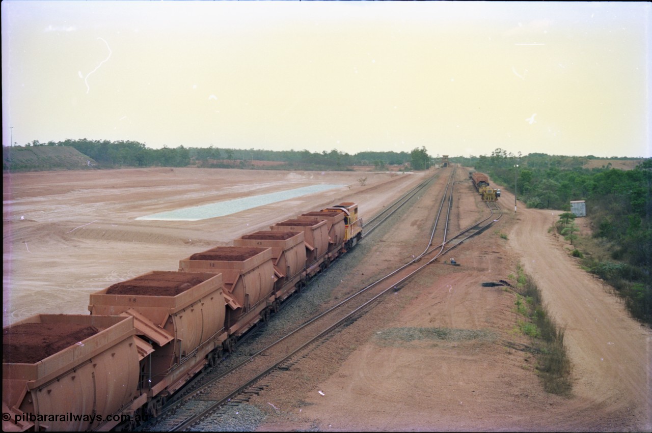 212-22
Weipa, a loaded train ex-Andoom Mine runs along the main with thirty two waggons at Lorim Point towards the dump station behind Comalco R 1001 Clyde Engineering built EMD model GT26C serial 72-752 originally numbered 1.001 and built in 1972. July 1995.
