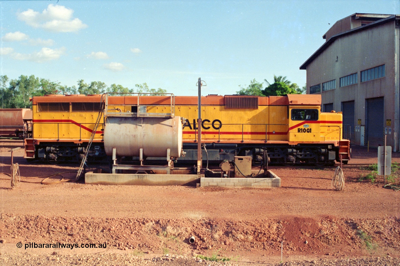 213-05
Weipa, Lorim Point fuel point looking south across the apron, Comalco R 1001 loco Clyde Engineering built EMD model GT26C serial 72-752 sits at the fuel point, items of note are these units were setup to have the long hood leading, the second 'tropical roof' and the five chime horn cut into the nose. Also noticeable, the units don't have dynamic brakes fitted so there is no brake 'blister' in the middle of the hood like you see on the GT26C models of WAGR L or VR C classes. September 1995.
Keywords: R1001;Clyde-Engineering;EMD;GT26C;72-752;1.001;Comalco;