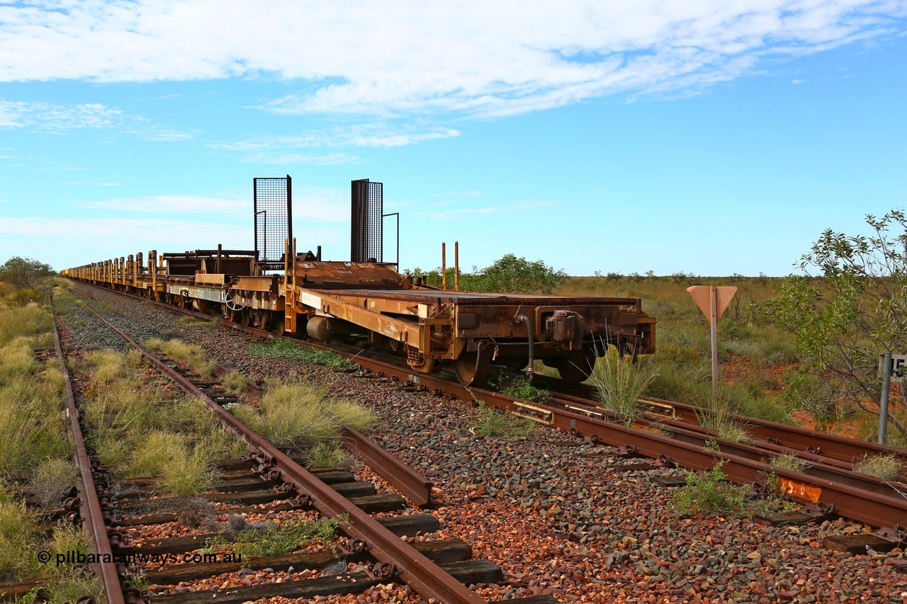 180614 1329
Allen Siding, at the 45 km looking east, the original rail or steel train is stowed on the mainline, looking from 1st lead off waggon 6011, built by Scotts of Ipswich 04-09-1970, the mesh guarding is for the winch cable. The chute arrangement for the discharging and recovery of rail is visible. 14th June 2018. [url=https://goo.gl/maps/UE2dRkZvdBr]GeoData[/url].
