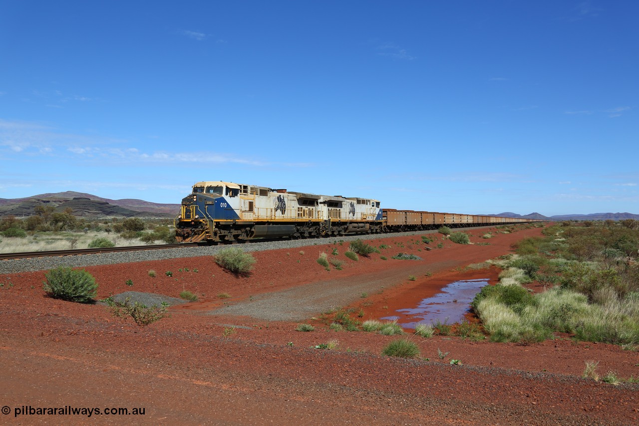 150507 8046
FMG Solomon Line, as the Nanutarra - Wittenoom Road was realigned when this line was built, this is where the western shortcut branch of the Roebourne - Wittenoom Road crosses the line before rejoining the Nanutarra Road. A loaded train behind double General Electric Dash Dash 9-44CW Co-Co locomotives, units 010 serial no. 58187 and 014 serial no. 58191 power a loaded along the straight, there are bank engines on the rear. Geodata: [url=https://goo.gl/maps/upAfsxGcMED2] -22.1617767 118.1279150 [/url].
