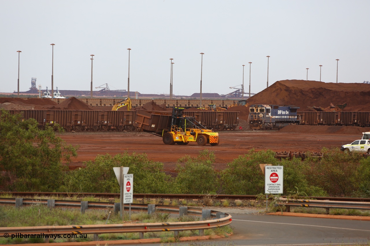 150523 8234
Nelson Point Yard, I Area, waggon scrapping by Sims Metal, a fork lift carries waggon no. 3340, one of 350 waggons built in Romania of which only about 60 made it into service, the rest rusting away in a caged embargo area out on the Broome Road until they were scrapped some years ago. There is a connection with these waggons and Lang Hancock and his former mine McCamey's Monster, now known as Jimblebar. 5665 looks on, its days also numbered.
Keywords: Arad-Romania;BHP-ore-waggon;