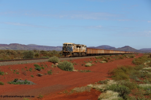 150507 8043
FMG Solomon Line, as the Nanutarra - Wittenoom Road was realigned when this line was built, this is where the western shortcut branch of the Roebourne - Wittenoom Road crosses the line before rejoining the Nanutarra Road. A loaded train behind double General Electric Dash 9-44CW Co-Co locomotives, units 010 serial no. 58187 and 014 serial no. 58191 power a loaded along the straight, there are bank engines on the rear. Geodata: [url=https://goo.gl/maps/upAfsxGcMED2] -22.1617767 118.1279150 [/url].
