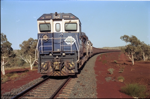 196-10
Yandi Two loaded car side of the loadout balloon loop, BHP Iron Ore CM40-8M or Dash 8 motive power in the form of 5658 'Kakogawa' serial 8412-03 / 94-149 rebuilt by Goninan as GE model CM40-8M from ALCo M636C number 5480 and two new Goninan built GE CM39-8 units 5630 'Zeus' serial 5831-09 / 88-079 and 5631 'Apollo' serial 5831-10 / 88-080 are the head end power with another two CM40-8M units mid-train. Train length is 240 waggons with a 120/120 split. Yandi Two ore stockpile and pedestal stacker boom tip visible in the background, the loadout operates via gravity and the train travels through a tunnel. May 1998.
Keywords: 5658;Goninan;GE;CM40-8M;8412-03/94-149;rebuild;AE-Goodwin;ALCo;M636C;5480;G6061-1;