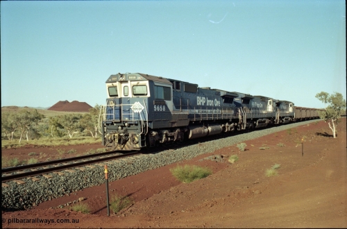 196-13
Yandi Two loaded car side of the loadout balloon loop, BHP Iron Ore CM40-8M or Dash 8 motive power in the form of 5658 'Kakogawa' serial 8412-03 / 94-149 rebuilt by Goninan as GE model CM40-8M from ALCo M636C number 5480 and two new Goninan built GE CM39-8 units 5630 'Zeus' serial 5831-09 / 88-079 and 5631 'Apollo' serial 5831-10 / 88-080 are the head end power with another two CM40-8M units mid-train. Train length is 240 waggons with a 120/120 split. Yandi Two ore stockpile and pedestal stacker boom tip visible in the background, the loadout operates via gravity and the train travels through a tunnel. May 1998.
Keywords: 5658;Goninan;GE;CM40-8M;8412-03/94-149;rebuild;AE-Goodwin;ALCo;M636C;5480;G6061-1;
