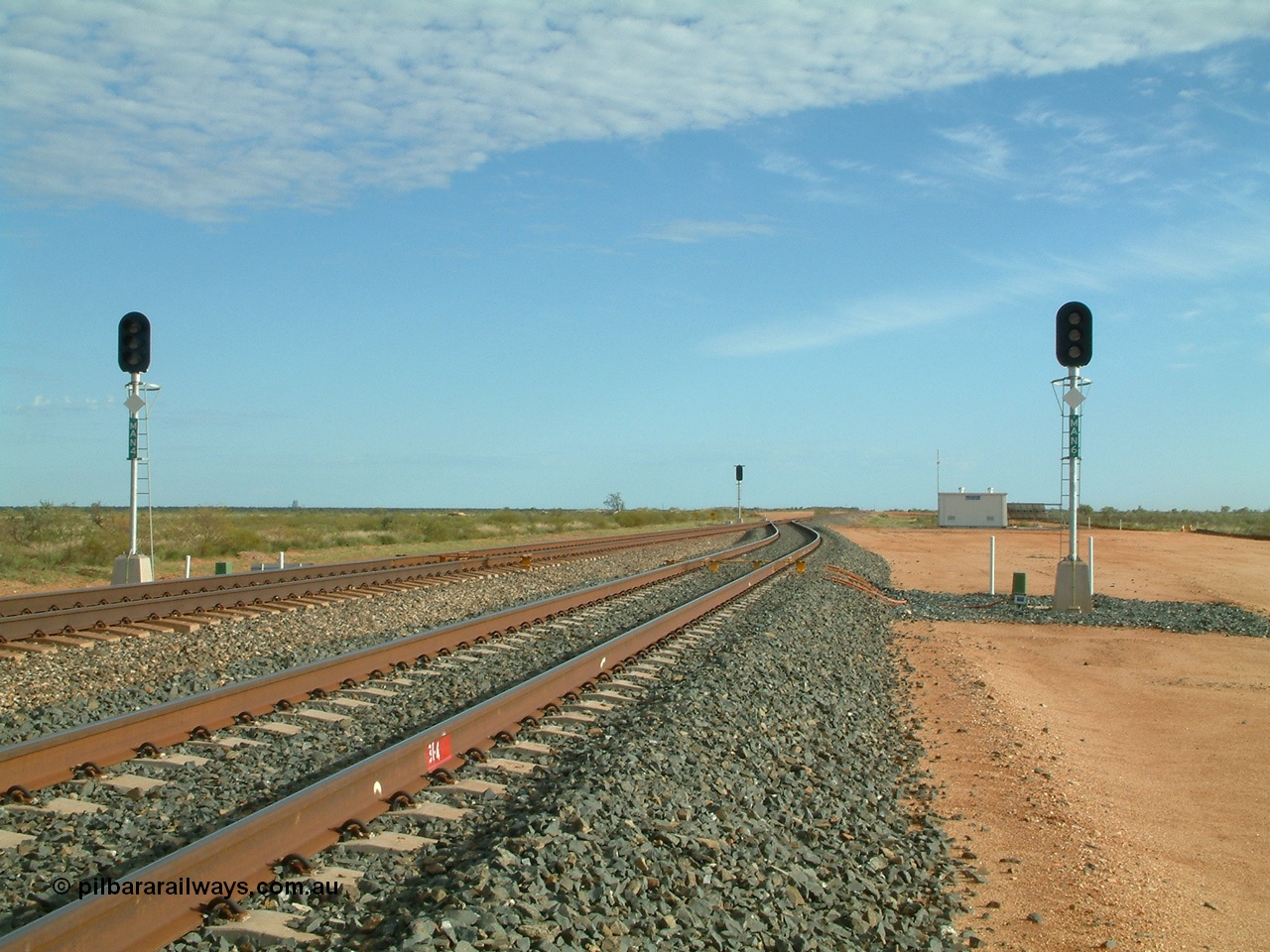 040407 075405
Mooka Siding, north end looking north, 31.4 km showing the standard layout of the track when it was single track with passing sidings, MAN 4 on the left is the mainline departure and MAN 6 in the passing track departure, all LED type. The DED 'dragging equipment detection' bars are visible along with the arrival signal and relay room. 7th April 2004.
