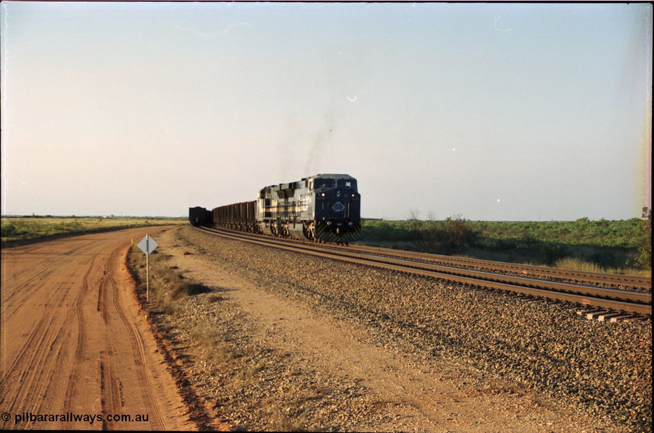203-01
Bing Siding, an empty train behind BHP General Electric AC6000 unit 6076 'Mt Goldsworthy' serial 51068 runs around the passing track with a loaded train on the mainline.
