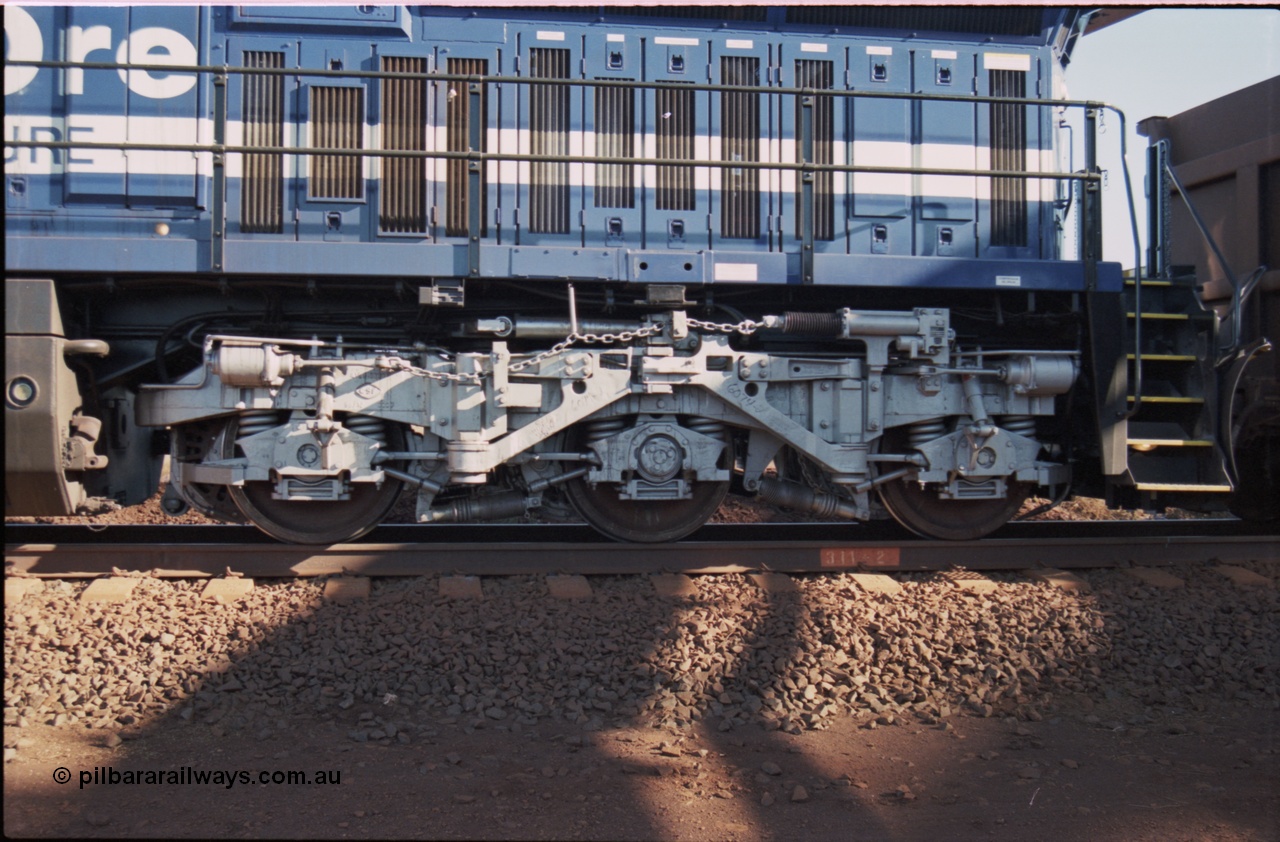 207-13
BHP General Electric built AC6000 unit 6074 serial 51066, brand new and unnamed at Yandi One load-out loop as a remote mid-train unit view of left hand side rear steerable bogie and air intakes below radiator.
Keywords: 6074;GE;AC6000;51066;