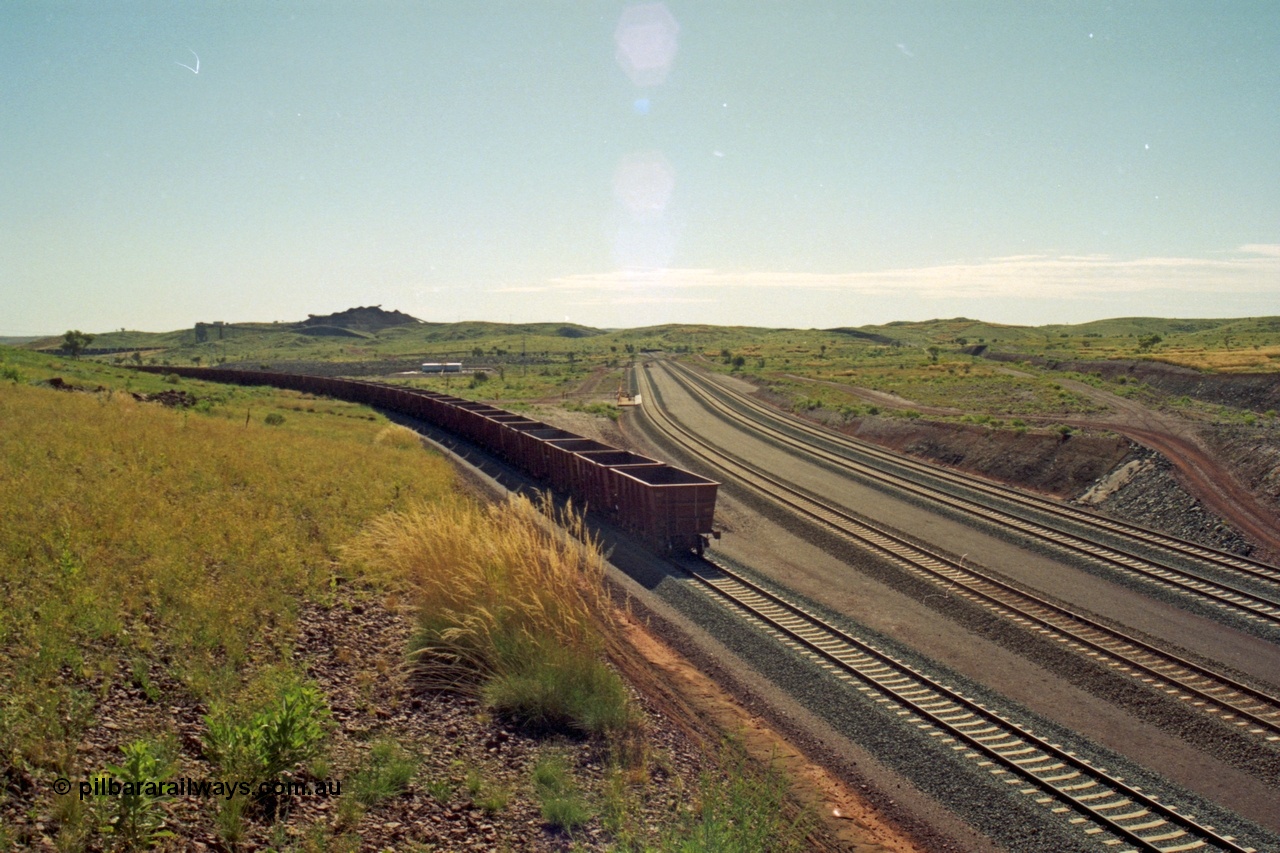 218-29
Yandicoogina or HIY as Hamersley Iron identify it, located 445 km from Parker Point yard in Dampier, view looking at rear of empty train being loaded with fuel tanks and loco fuel point in middle of frame and mine stockpiles in the background.
