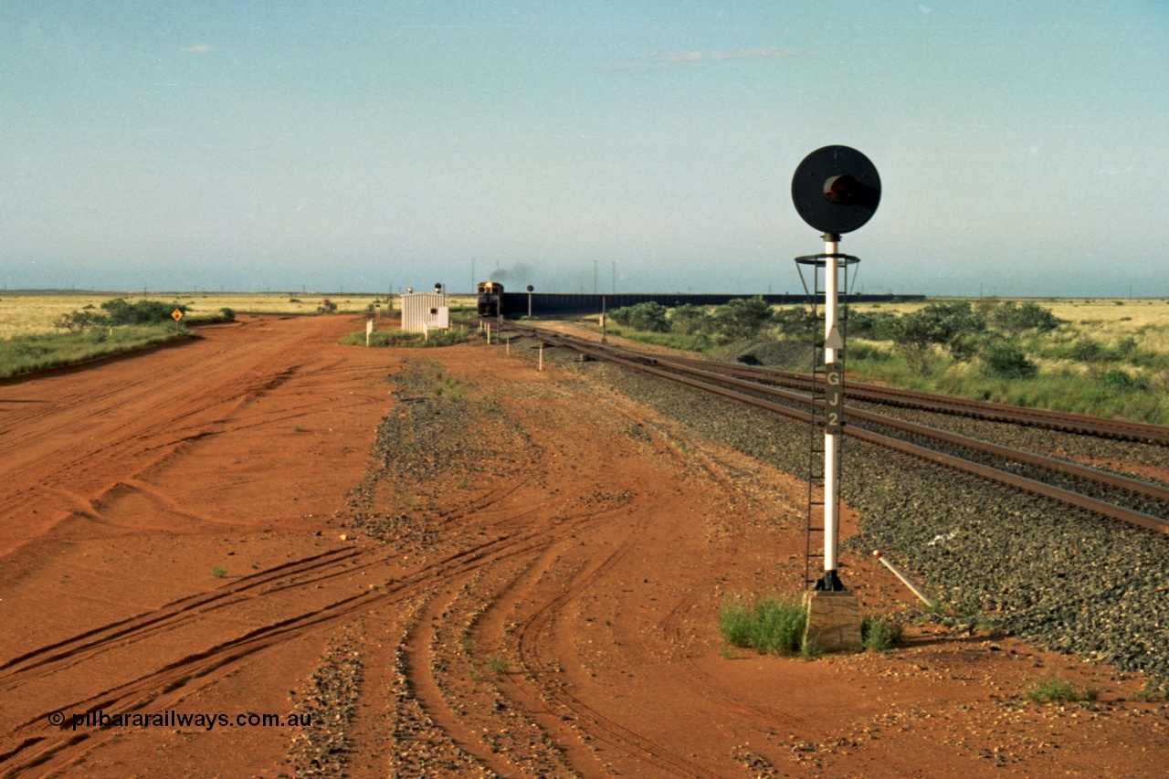 220-28
Goldsworthy Junction, an empty train on the Newman line approaches having departed Nelson Point. The line merging in from the right is the Goldsworthy line to Yarrie and Nimingarra, which can then be made out diverging to the left just after the interlocking room in front of the train.
