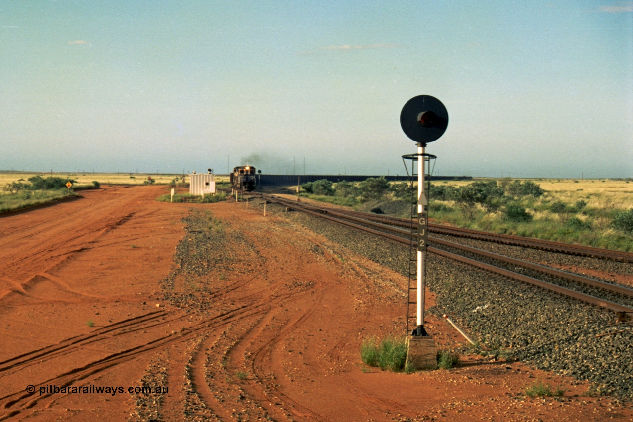 220-29
Goldsworthy Junction, an empty train on the Newman line approaches having departed Nelson Point. The line merging in from the right is the Goldsworthy line to Yarrie and Nimingarra, which can then be made out diverging to the left just after the interlocking room in front of the train.
