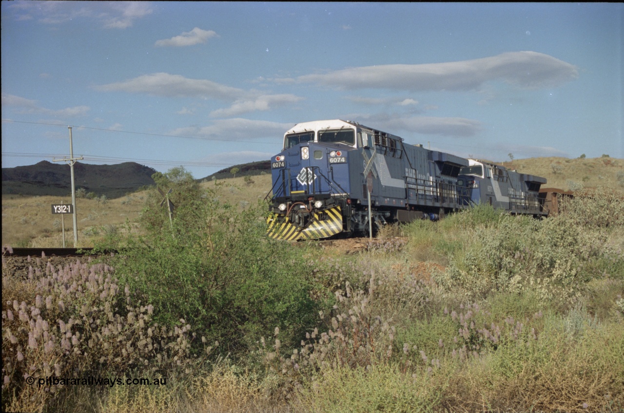 221-30
Yandi One mine loadout balloon loop, near new General Electric AC6000 unit 6074 serial 51066 leads sister unit 6071 serial 51063 at the Y312.1 km crossing while controlling a train being loaded.
Keywords: 6074;GE;AC6000;51066;