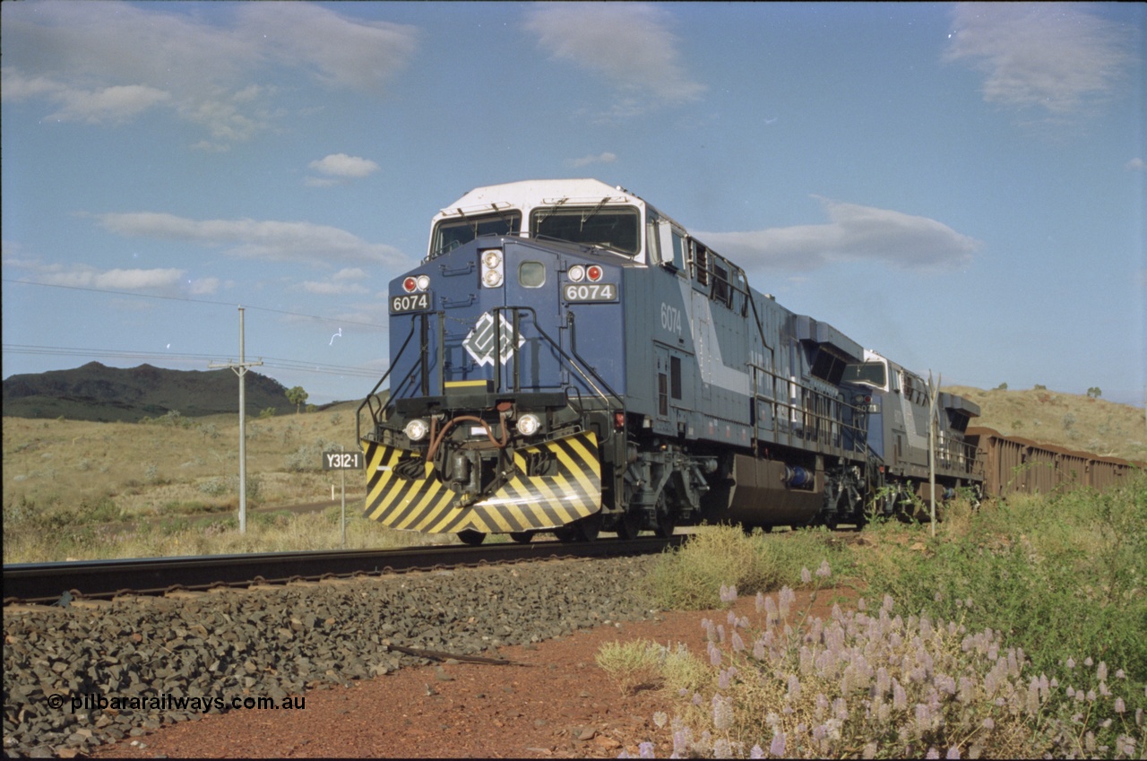 221-32
Yandi One mine loadout balloon loop, near new General Electric AC6000 unit 6074 serial 51066 leads sister unit 6071 serial 51063 at the Y312.1 km crossing while controlling a train being loaded.
Keywords: 6074;GE;AC6000;51066;