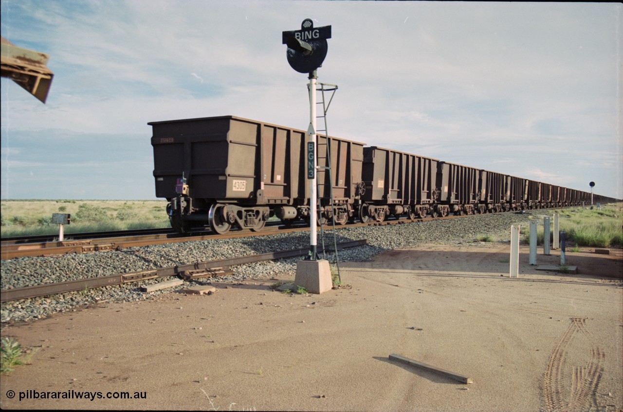 225-09
Bing siding, signal post BGN 3 stand sentinel as the end of the afternoon Yandi train is seen heading south with last waggon 4305, one of 126 such waggons constructed during 1997 out of 3CR12 stainless steel in an effort to eliminate painting and to reduce wear on the waggon body. This design was designated HC7081. [url=https://goo.gl/maps/r3bVfZz8aJS2]GeoData[/url].
Keywords: 4305;United-Goninan-WA;3CR12;HC7081;