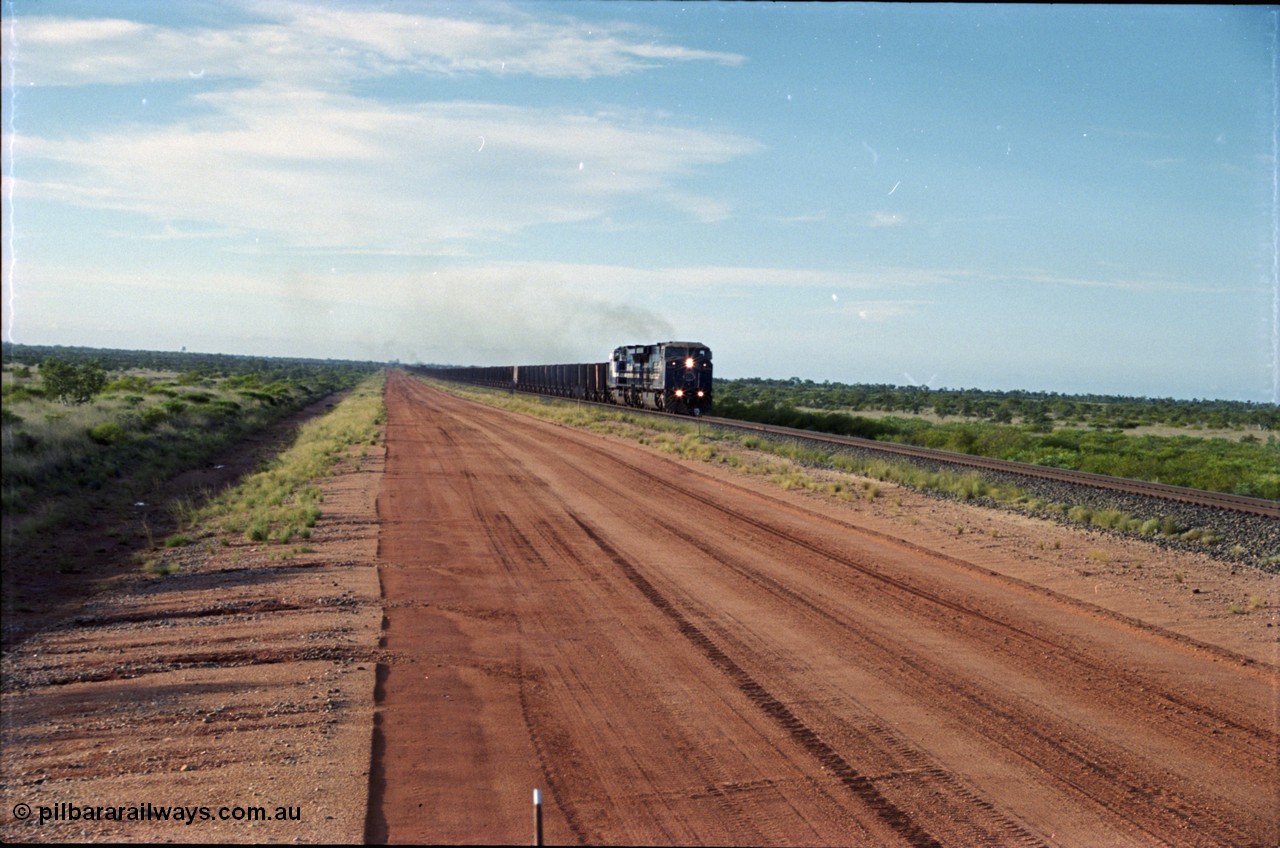 225-16
At the 24.1 km grade crossing on the BHP Newman line, the afternoon departure for Yandi mine heads south behind the standard double General Electric AC6000 units with another AC6000 unit mid-train. [url=https://goo.gl/maps/qGkyfiuy6212]GeoData[/url].
