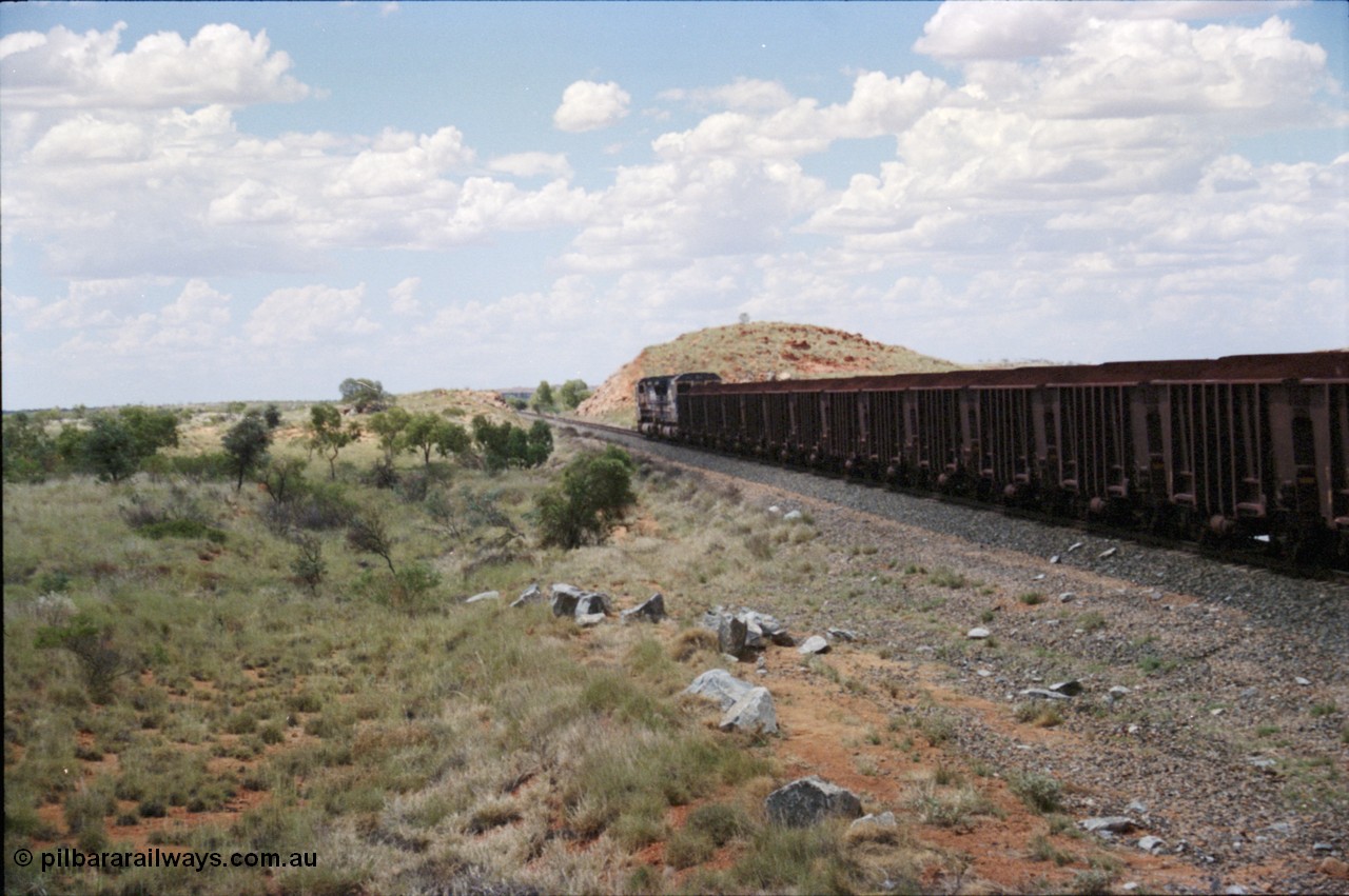 226-08
Redmont, 202 km with a loaded Yandi train speeding north towards the port behind a pair of CM40-8M locomotives with the distinctive flat top loading profile of the Yandi loadouts. [url=https://goo.gl/maps/HYx9nXwpXfP2]GeoData[/url].
