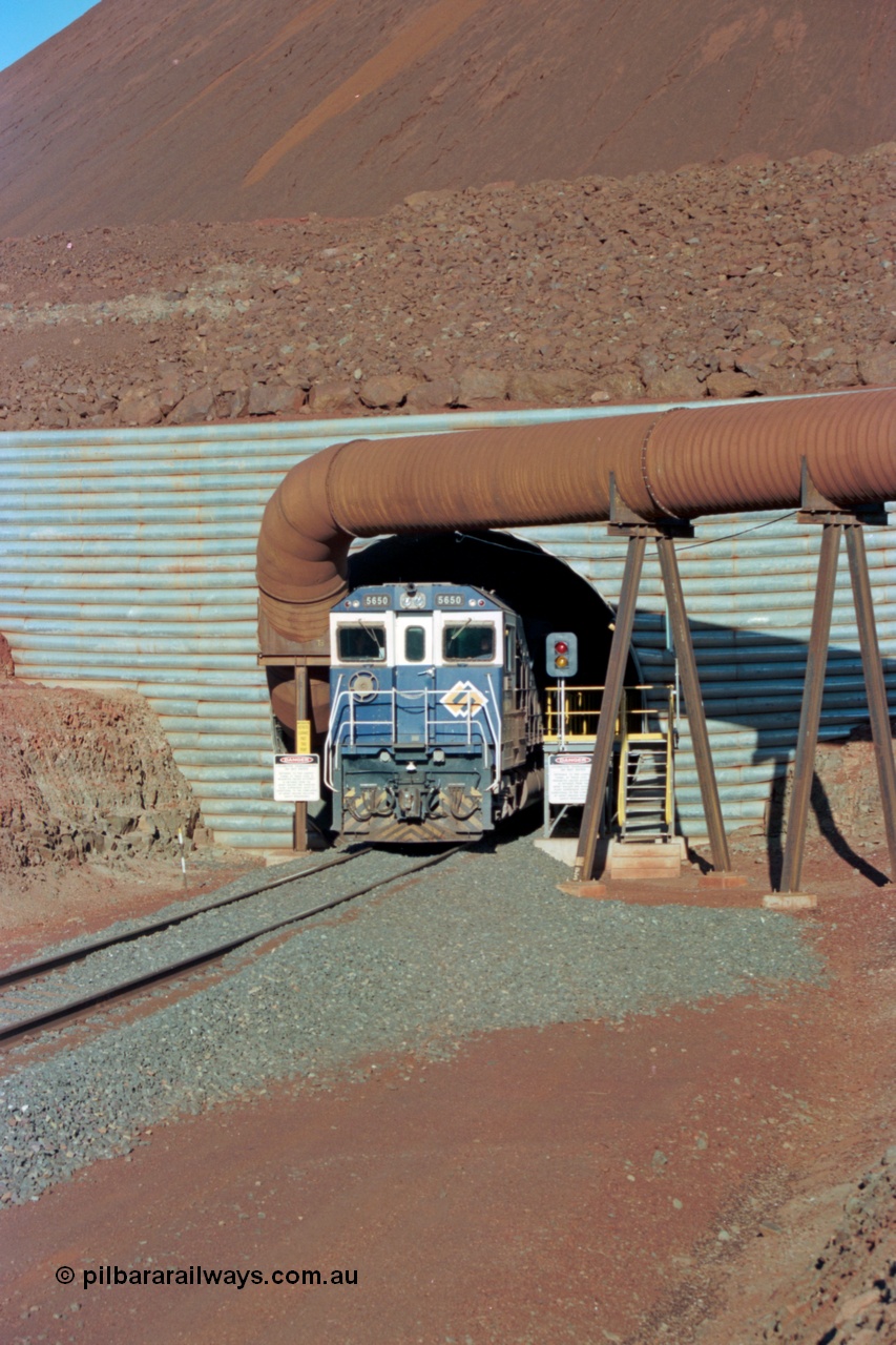 229-16
Yandi Two loadout, looking at the exit portal of the tunnel as Goninan rebuild CM40-8M GE unit 5650 'Yawata' serial 8412-07 / 93-141 drags a loading through at 1.2 km/h, the massive pile of ore is gravity fed into the waggons via two sets of hydraulic chutes, the red and amber lights control access through the tunnel and the steel pipe is for dust extraction. [url=https://goo.gl/maps/jmtnauf76Zq]GeoData[/url].
Keywords: 5650;Goninan;GE;CM40-8M;8412-07/93-141;rebuild;AE-Goodwin;ALCo;M636C;5481;G6061-2;