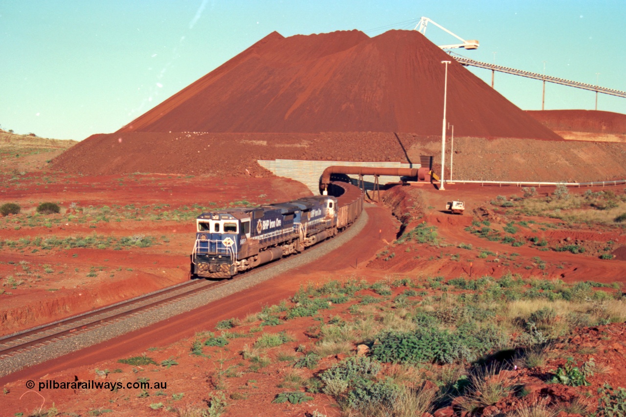 229-26
Yandi Two loadout exit side, as Goninan rebuild CM40-8M GE unit 5650 'Yawata' serial 8412-07 / 93-141 with sister unit 5642 drag a loading train at 1.2 km/h, the massive pile of ore is gravity fed into the waggons via two sets of hydraulic chutes, the original pedestal radial stacker is visible above the ore along with the extraction fan. [url=https://goo.gl/maps/KQ3dQNrTwd42]GeoData[/url].
Keywords: 5650;Goninan;GE;CM40-8M;8412-07/93-141;rebuild;AE-Goodwin;ALCo;M636C;5481;G6061-2;