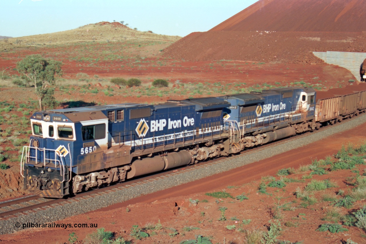 229-27
Yandi Two loadout exit side, Goninan rebuild CM40-8M GE units 5650 'Yawata' serial 8412-07 / 93-141 and sister unit 5642 drag a loading train at 1.2 km/h, both units carry the BHP Iron Ore teal and marigold livery for the logo. [url=https://goo.gl/maps/KQ3dQNrTwd42]GeoData[/url].
Keywords: 5650;Goninan;GE;CM40-8M;8412-07/93-141;rebuild;AE-Goodwin;ALCo;M636C;5481;G6061-2;
