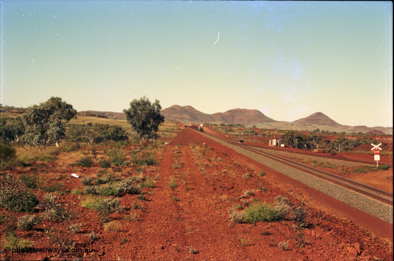 230-00
Yandi Two switch looking east with the Three Sisters forming the background. Empty BHP train heading for the balloon loop for loading, grade crossing is the YT 311.5 km. Geodata [url=https://goo.gl/maps/DcycDGojcBt] -22.713725, 119.055762 [/url].
