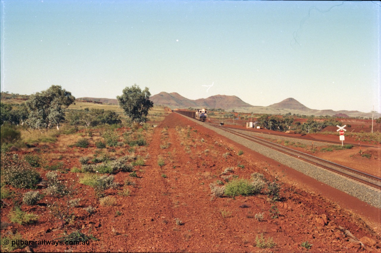 230-03
Yandi Two switch looking east with the Three Sisters forming the background. Empty BHP train heading for the balloon loop for loading, grade crossing is the YT 311.5 km. Geodata [url=https://goo.gl/maps/DcycDGojcBt] -22.713725, 119.055762 [/url].
