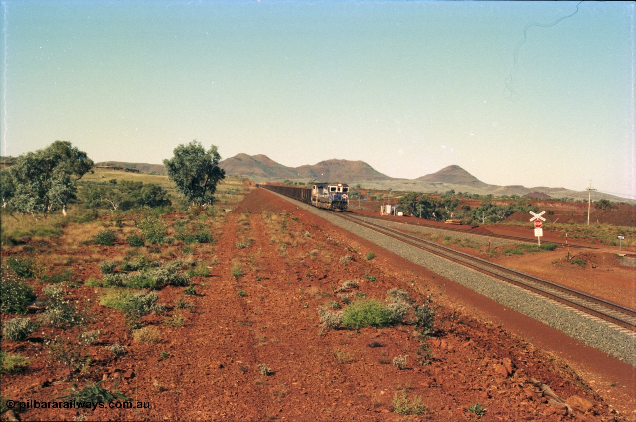 230-05
Yandi Two switch looking east with the Three Sisters forming the background. Empty BHP train heading for the balloon loop for loading, grade crossing is the YT 311.5 km. Geodata [url=https://goo.gl/maps/DcycDGojcBt] -22.713725, 119.055762 [/url].
