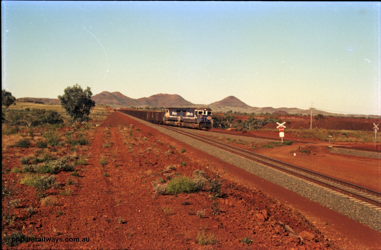 230-07
Yandi Two switch looking east with the Three Sisters forming the background. Empty BHP train with dual CM40-8M units on the point, heading for the balloon loop for loading, grade crossing is the YT 311.5 km. Geodata [url=https://goo.gl/maps/DcycDGojcBt] -22.713725, 119.055762 [/url].
