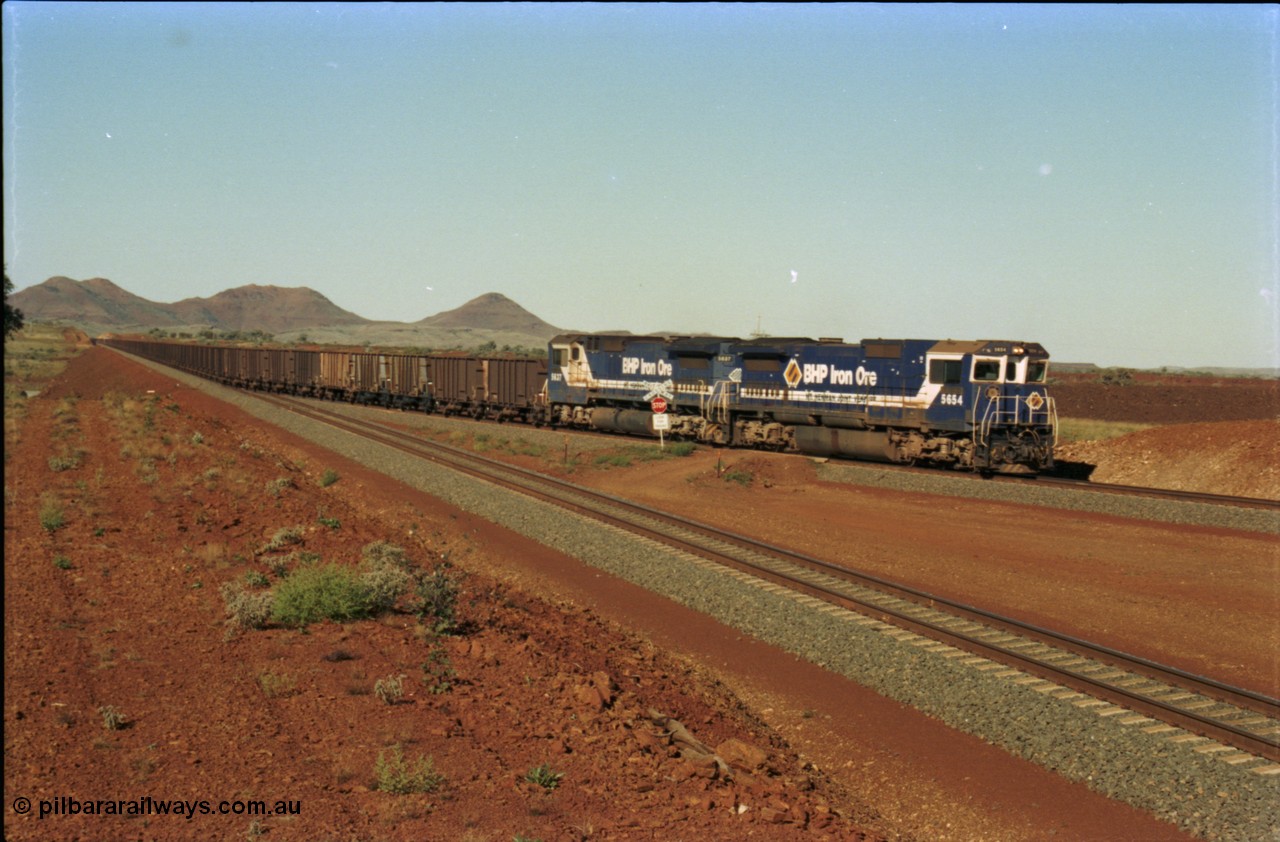 230-08
Yandi Two switch looking east with the Three Sisters forming the background. Empty BHP train behind CM40-8M units 5654 and 5637 crossing the YT 311.5 km grade crossing. Geodata [url=https://goo.gl/maps/DcycDGojcBt] -22.713725, 119.055762 [/url].
