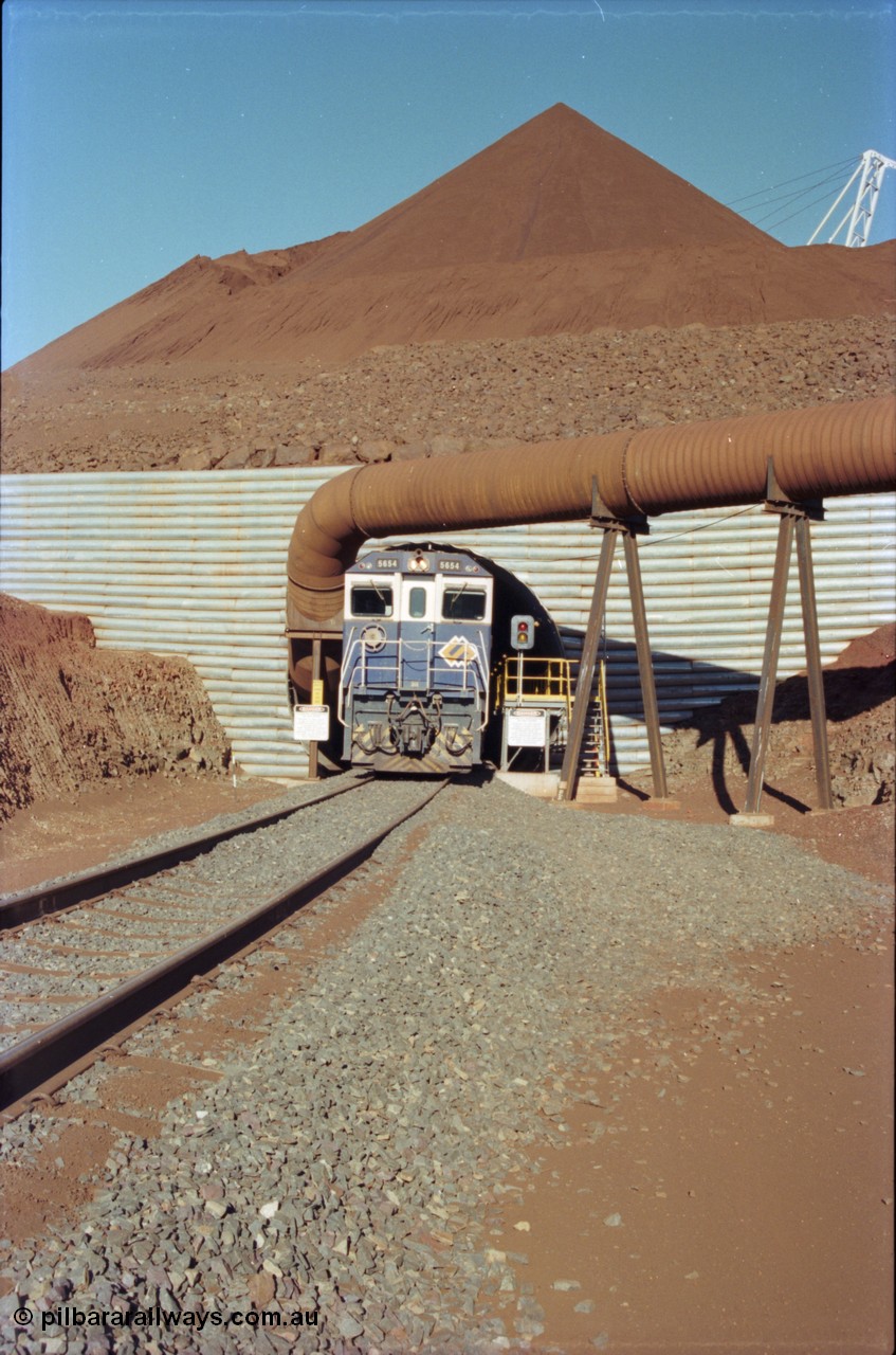 230-13
Yandi Two load-out tunnel exit side portal, Goninan rebuild GE CM40-8M model 5654 'Kashima' serial 8412-11/93-145 creeps out of the tunnel as its train is loaded at 1.2 km/h. The livery is the marigold version of the BHP Australia logo. Geodata [url=https://goo.gl/maps/h68ia1caJvL2] -22.718338, 119.039909 [/url].
Keywords: 5654;Goninan;GE;CM40-8M;8412-11/93-145;rebuild;Comeng-NSW;ALCo;M636C;5493;C6084-9;