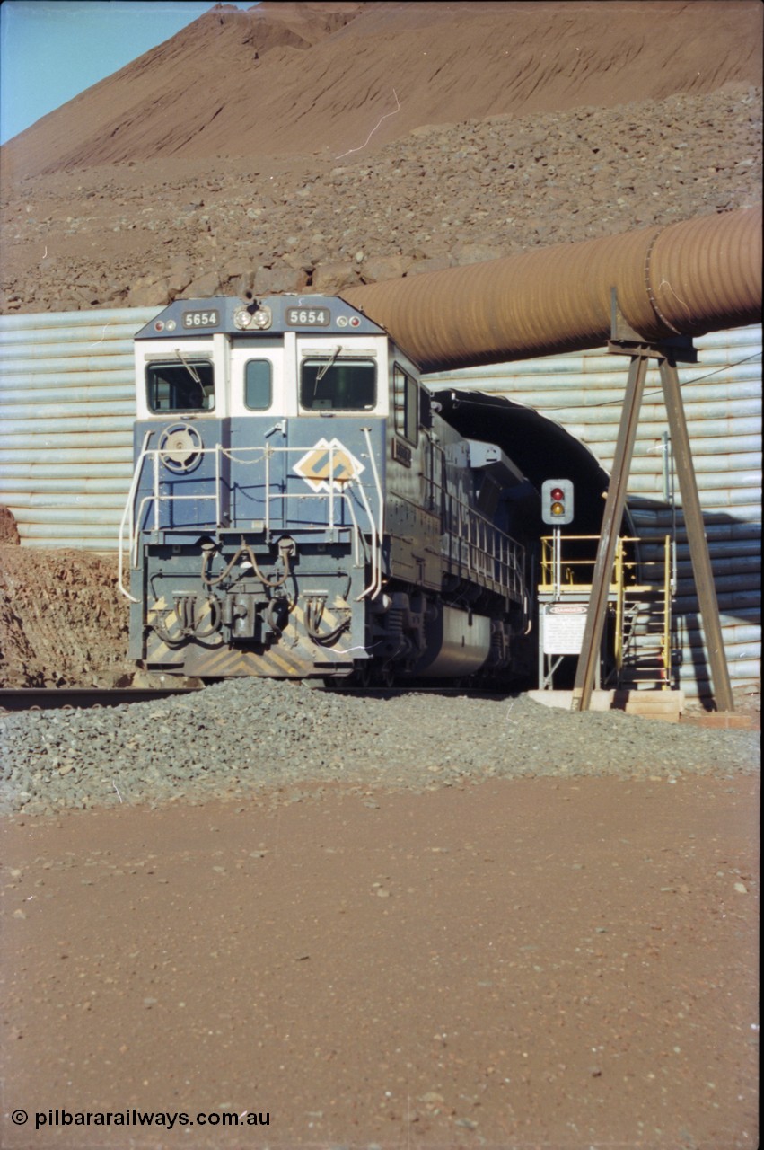 230-14
Yandi Two load-out tunnel exit side portal, Goninan rebuild GE CM40-8M model 5654 'Kashima' serial 8412-11/93-145 creeps out of the tunnel as its train is loaded at 1.2 km/h. The livery is the marigold version of the BHP Australia logo. Geodata [url=https://goo.gl/maps/h68ia1caJvL2] -22.718338, 119.039909 [/url].
Keywords: 5654;Goninan;GE;CM40-8M;8412-11/93-145;rebuild;Comeng-NSW;ALCo;M636C;5493;C6084-9;