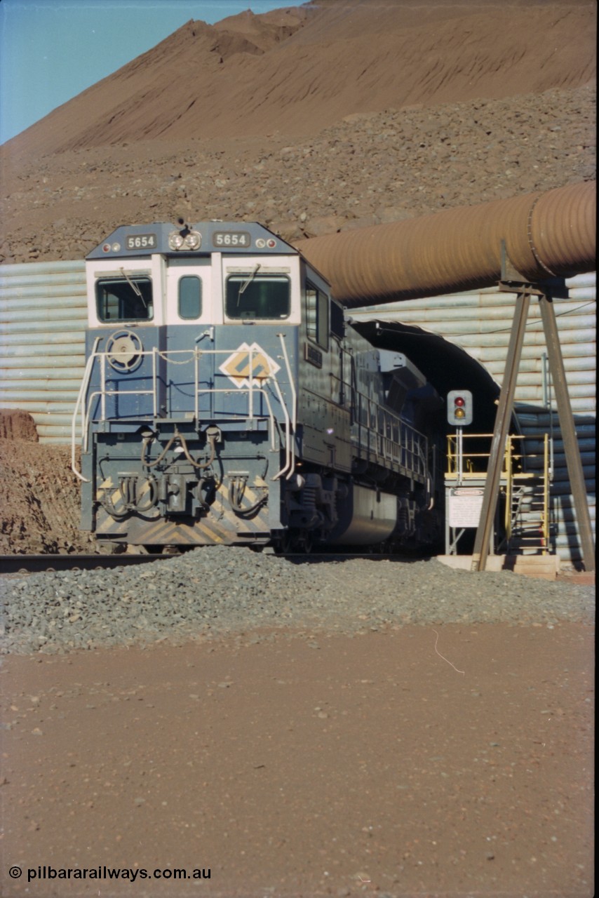 230-15
Yandi Two load-out tunnel exit side portal, Goninan rebuild GE CM40-8M model 5654 'Kashima' serial 8412-11/93-145 creeps out of the tunnel as its train is loaded at 1.2 km/h. The livery is the marigold version of the BHP Australia logo. Geodata [url=https://goo.gl/maps/h68ia1caJvL2] -22.718338, 119.039909 [/url].
Keywords: 5654;Goninan;GE;CM40-8M;8412-11/93-145;rebuild;Comeng-NSW;ALCo;M636C;5493;C6084-9;