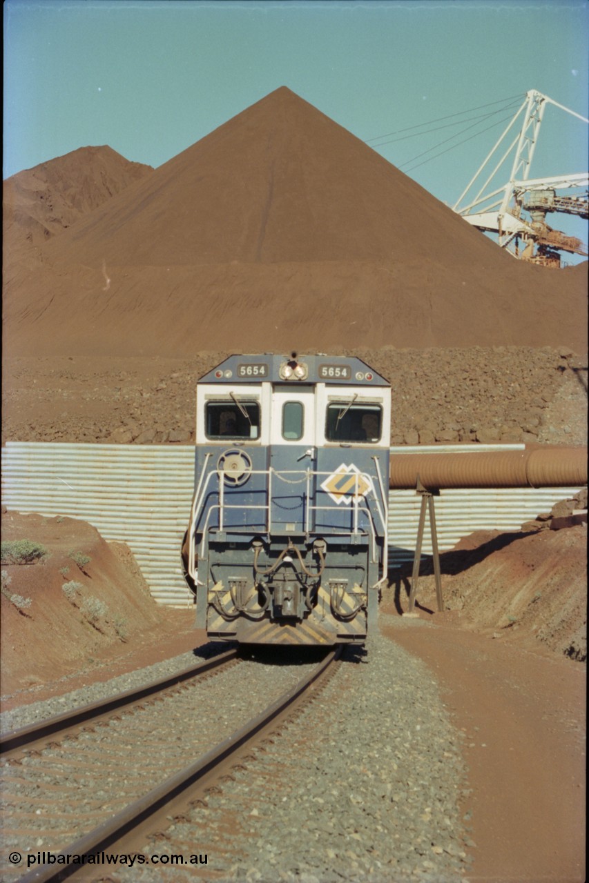 230-20
Yandi Two load-out tunnel exit side portal, Goninan rebuild GE CM40-8M model 5654 'Kashima' serial 8412-11/93-145 leads a loading train 1.2 km/h. The ore stockpile and pedestal stacker are visible. The livery is the marigold version of the BHP Australia logo. Geodata [url=https://goo.gl/maps/h68ia1caJvL2] -22.718338, 119.039909 [/url].
Keywords: 5654;Goninan;GE;CM40-8M;8412-11/93-145;rebuild;Comeng-NSW;ALCo;M636C;5493;C6084-9;