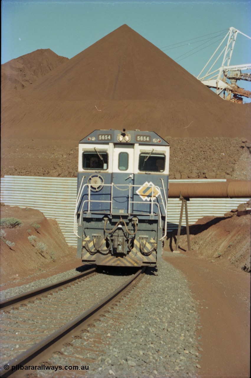 230-21
Yandi Two load-out tunnel exit side portal, Goninan rebuild GE CM40-8M model 5654 'Kashima' serial 8412-11/93-145 leads a loading train 1.2 km/h. The ore stockpile and pedestal stacker are visible. The livery is the marigold version of the BHP Australia logo. Geodata [url=https://goo.gl/maps/h68ia1caJvL2] -22.718338, 119.039909 [/url].
Keywords: 5654;Goninan;GE;CM40-8M;8412-11/93-145;rebuild;Comeng-NSW;ALCo;M636C;5493;C6084-9;