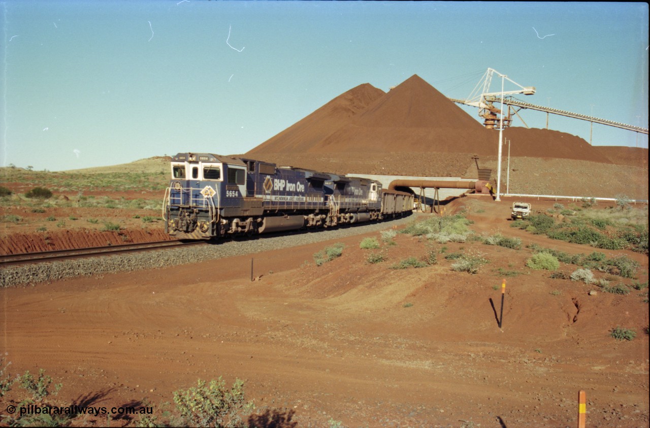 230-25
Yandi Two balloon loop, view of the stockpile area and pedestal stacker, train being loaded at 1.2 km/h behind two Goninan GE CM40-8M rebuilds from different ALCo builders. 5654 'Kashima' serial 8412-11/93-145 is from Comeng ALCo M636 unit 5493 while 5637 'De Grey' serial 8181-01/92-123 is from an AE Goodwin ALCo C636 unit 5456. Geodata [url=https://goo.gl/maps/h68ia1caJvL2] -22.718338, 119.039909 [/url].
Keywords: 5654;Goninan;GE;CM40-8M;8412-11/93-145;rebuild;Comeng-NSW;ALCo;M636C;5493;C6084-9;